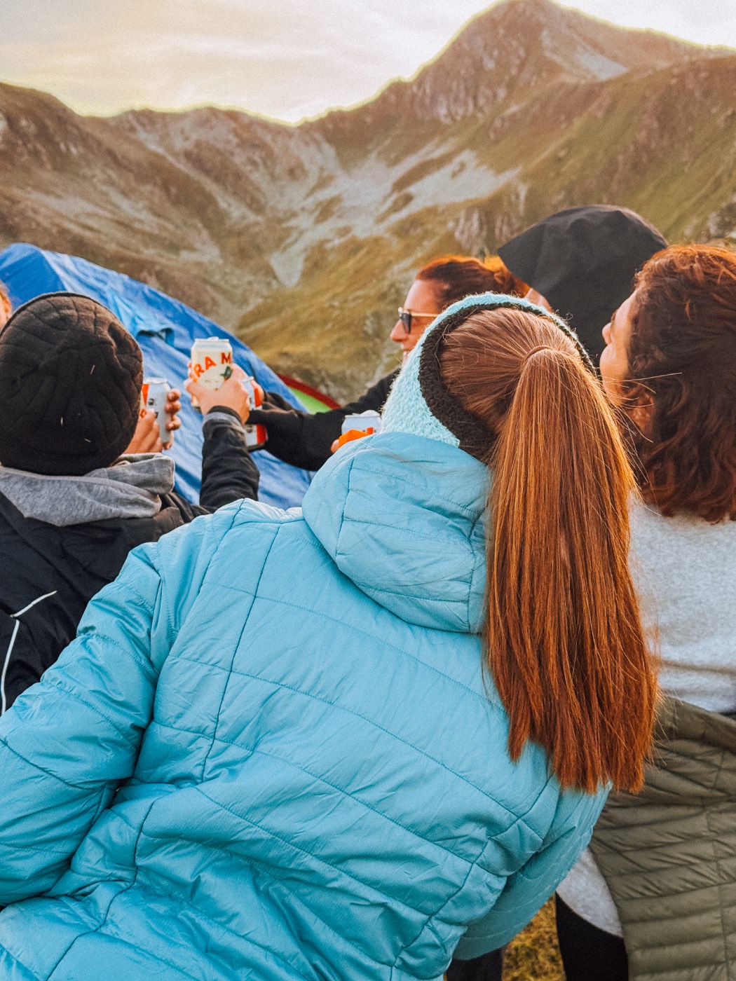 Un gruppo brinda davanti alle tende, con le creste di montagna alle spalle