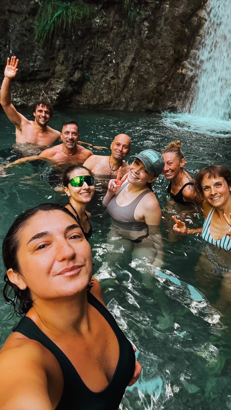 Selfie di gruppo in una pozza d'acqua sotto una cascata